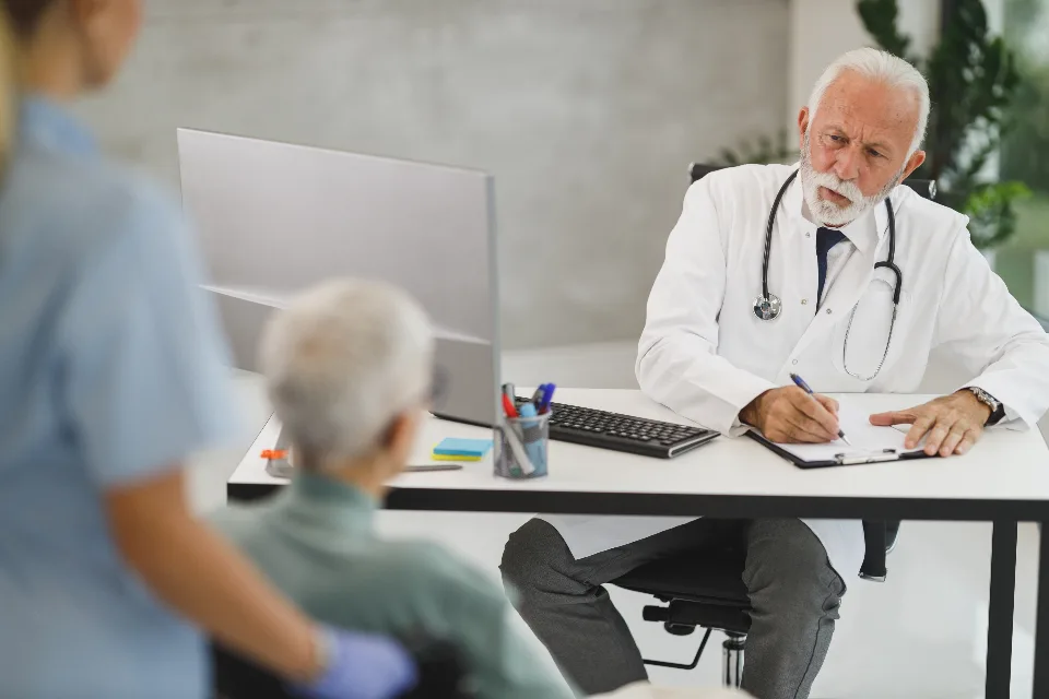 Physician reviewing claim paperwork with patients at a desk