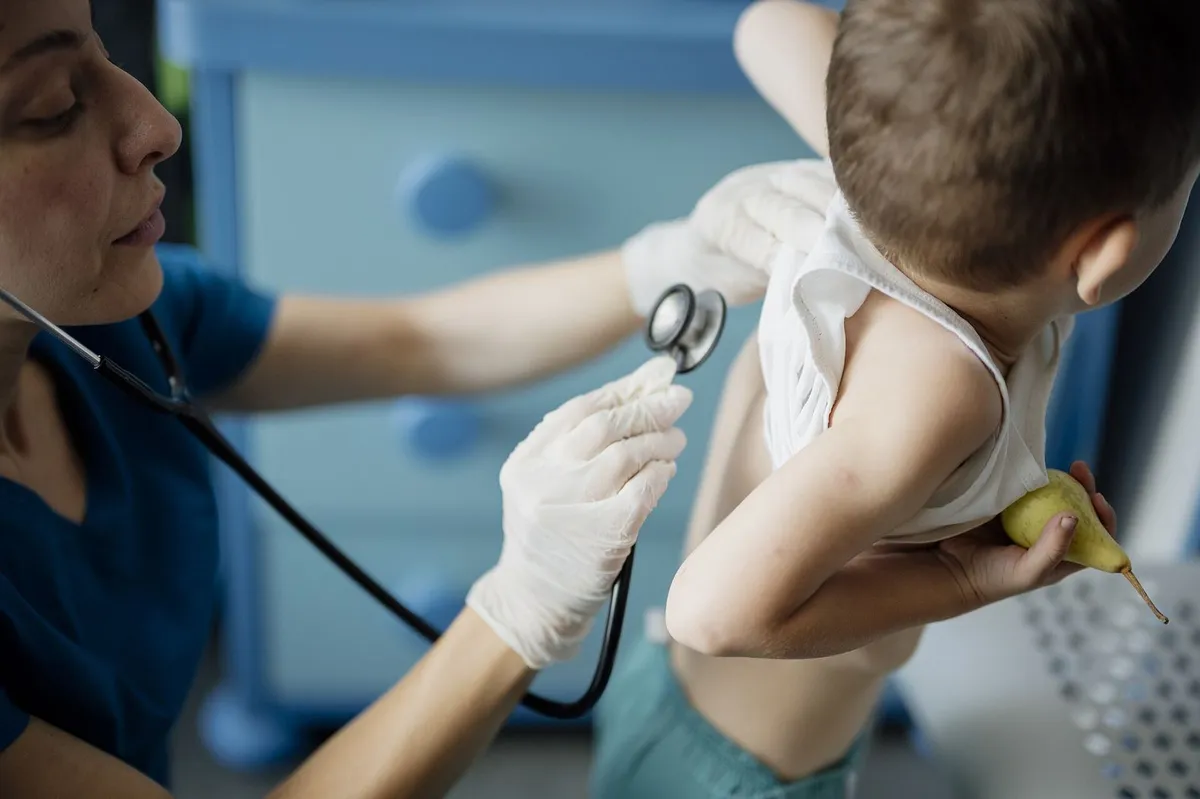 Pediatrician examining a young boy with a stethoscope in a modern clinic